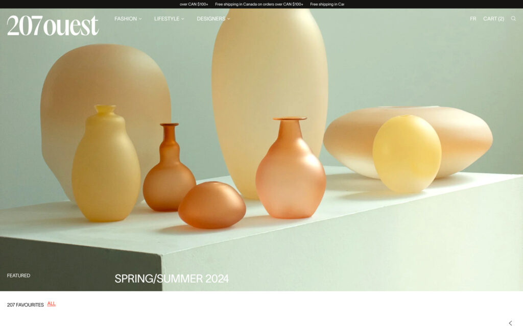 The image showcases a collection of blown glass vases in soft, pastel hues, arranged on a white shelf. The shapes range from round to elongated, evoking a modern and artistic atmosphere suitable for the Spring/Summer 2024 season.